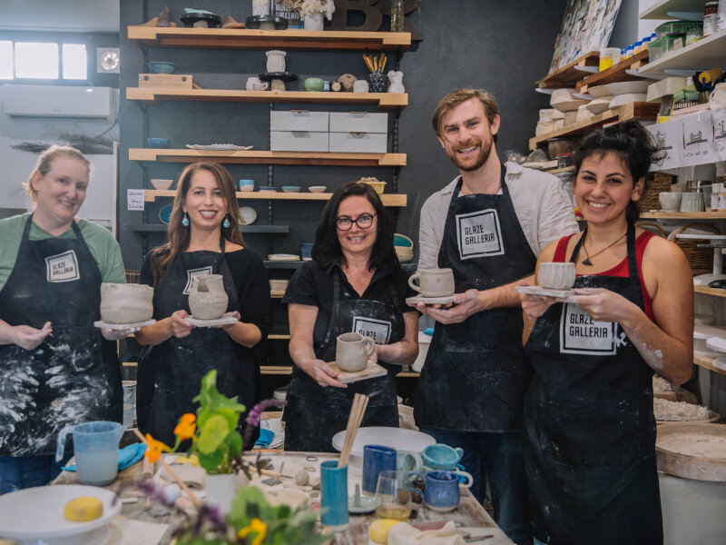 A group of people holding handmade pottery.